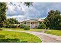 Brick home with circular driveway, manicured lawn, and mature trees at 6779 Clayton St, Mount Dora, FL 32757