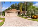 Single story home with beige exterior, paver driveway and lush landscaping at 7151 Se 173Rd Arlington Loop, The Villages, FL 32162