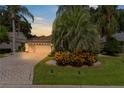 One-story house with paver driveway, landscaping, and palm trees at dusk at 7151 Se 173Rd Arlington Loop, The Villages, FL 32162