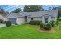 Single-story home with gray siding, a gray garage door, and well-manicured lawn at 3912 Plantation Blvd, Leesburg, FL 34748