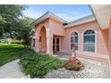 Peach-colored house with arched entryway and neatly landscaped yard at 36649 Sundance Dr, Grand Island, FL 32735