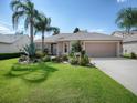 Cute house with a well-manicured lawn and palm trees at 616 Cokesbury Dr, The Villages, FL 32162