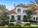 Mediterranean style home with stucco exterior, tile roof, and lush landscaping at 15008 Pendio Dr, Bella Collina, FL 34756