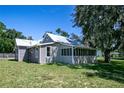 Rear view of renovated home with grey siding and screened porch at 19402 E 5Th St, Umatilla, FL 32784