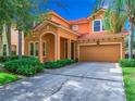 Two-story house with orange exterior, two-car garage, and lush landscaping at 426 Orange Cosmos Blvd, Davenport, FL 33837