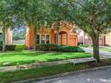 Two-story house with orange exterior, two-car garage, and lush landscaping at 426 Orange Cosmos Blvd, Davenport, FL 33837