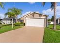 Tan house with a two-car garage and nicely landscaped yard at 1785 Bassinger Ct, The Villages, FL 32162