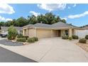 Front view of a tan one-story house with a two-car garage at 16888 Se 73Rd Tim Ter, The Villages, FL 32162