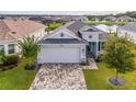 White house with gray roof, stone accents, and a paved driveway at 8492 Hartford Way, Mount Dora, FL 32757