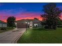 Single-story house with attached garage and well-maintained lawn at sunset at 5500 Belle Terre Dr, Leesburg, FL 34748