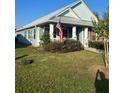 Light blue house with a covered porch, red shutters, and a metal roof at 104 Turtle Run, Umatilla, FL 32784