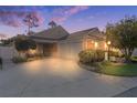 Tan house with two-car garage and landscaped front yard at 3930 E Torch Lake Dr, The Villages, FL 32163