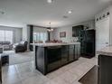 Modern kitchen with dark cabinets, island, and stainless steel appliances at 10548 Bronze Leaf Ct, Leesburg, FL 34788