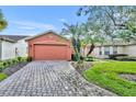 Single-story house with orange exterior, paver driveway, and landscaping at 540 Grand Canal Dr, Kissimmee, FL 34759
