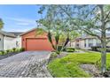 Single-story house with orange exterior, paver driveway, and landscaping at 540 Grand Canal Dr, Kissimmee, FL 34759