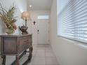Bright entryway with tiled floor, white door, and decorative console table at 5035 Stokes Way, Wildwood, FL 34785