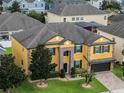 Aerial view of a two-story house with a yellow exterior, brown accents, and a two-car garage at 349 Morning View Dr, Winter Garden, FL 34787