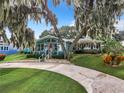 Teal home with a red door, landscaping, and a circular driveway at 1559 Lakeshore Dr, Eustis, FL 32726