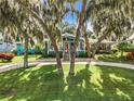 Teal home with a red door, landscaping, and a circular driveway at 1559 Lakeshore Dr, Eustis, FL 32726