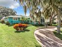 Teal home with a red door, landscaping, and a circular driveway at 1559 Lakeshore Dr, Eustis, FL 32726