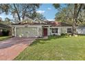 Single-story house with two-car garage, green lawn, and landscaping at 34321 Shadewood Cir, Leesburg, FL 34788