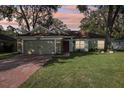 Single-story house with two-car garage, green lawn, and landscaping at dusk at 34321 Shadewood Cir, Leesburg, FL 34788