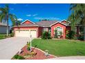 Red house with three-car garage and manicured lawn at 25611 Maurepas Ln, Leesburg, FL 34748