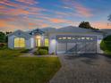 Single-story home with gray roof, two-car garage, and paved driveway at 425 Grand Vista Trl, Leesburg, FL 34748