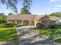 Tan one-story house with a brown roof, white columns, and manicured landscaping at 1861 Park Forest Blvd, Mount Dora, FL 32757