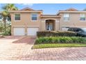 Tan two-story townhome with attached two-car garage and lush landscaping at 5279 Bowline Ct, Oxford, FL 34484