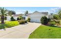 White house with gray roof and a two-car garage, landscaped yard at 586 Hartley Pl, The Villages, FL 32162