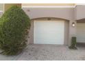 White garage door with brick pavers and lush green shrubbery at 3406 Soho St # 102, Orlando, FL 32835