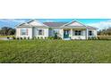 Exterior of a one-story home with light siding, landscaping, and a large yard at 38805 Ranch Gate Blvd, Umatilla, FL 32784