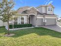 Two-story house with stone accents, three-car garage, and manicured lawn at 405 Amola Way, Howey In The Hills, FL 34737