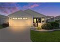 White house exterior at dusk with a two-car garage and landscaped front yard at 6084 Guy Ter, The Villages, FL 32163