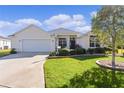 One-story house featuring a white exterior, neatly landscaped lawn, and a two-car garage at 1006 Sayle St, The Villages, FL 32162