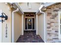 Stone and light beige exterior entryway with a glass front door at 10286 Julia Isles Ave, Oxford, FL 34484