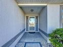 Front entry with a glass door and sidelights, stone flooring, and landscaping at 4634 Summerbridge Cir, Leesburg, FL 34748