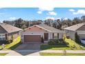 One-story home with brown garage door and well-manicured lawn at 29549 Caspian St, Leesburg, FL 34748