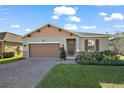 One-story home with brown garage door, landscaping, and brick pavers at 29549 Caspian St, Leesburg, FL 34748