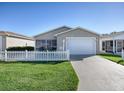 Tan house with white picket fence, one car garage, and nicely landscaped lawn at 409 Rose Croft Ter, The Villages, FL 32162