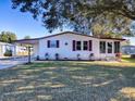 White single story home with carport, landscaping, and a spacious yard at 1611 Cherry Hill Rd, The Villages, FL 32159