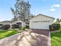 Exterior view of a single-story house with a two-car garage and a nicely landscaped front yard at 17449 Se 76Th Flintlock Ter, The Villages, FL 32162