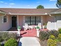 Brick front porch with rocking chairs, potted plants, and a red tile floor at 1621 Texas Ct, Tavares, FL 32778