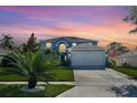 Two-story house with a gray exterior, white garage door, and landscaping at sunset at 1087 Welch Hill Cir, Apopka, FL 32712