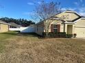 Landscaped side yard with a view of the house and fence at 9785 Pepper Tree Trl, Wildwood, FL 34785