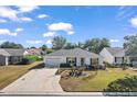 Single-story house with a driveway and lawn, aerial view at 2514 Raintree Dr, The Villages, FL 32162