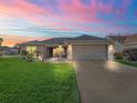 House exterior at dusk, showcasing landscaping and driveway at 3000 Saint Michael Ln, The Villages, FL 32162