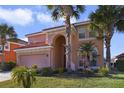 Two-story house with a pink facade, a three-car garage, and palm trees at 151 Rubino Dr, Davenport, FL 33837