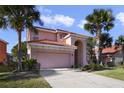 Two-story house with a pink facade, a three-car garage, and a large driveway at 151 Rubino Dr, Davenport, FL 33837